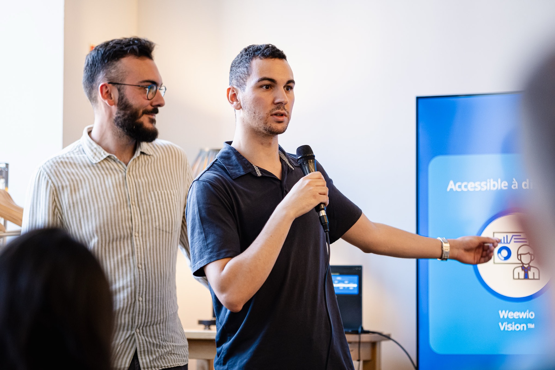 Deux porteurs de projet lauréats présentent leur solution au micro devant un écran