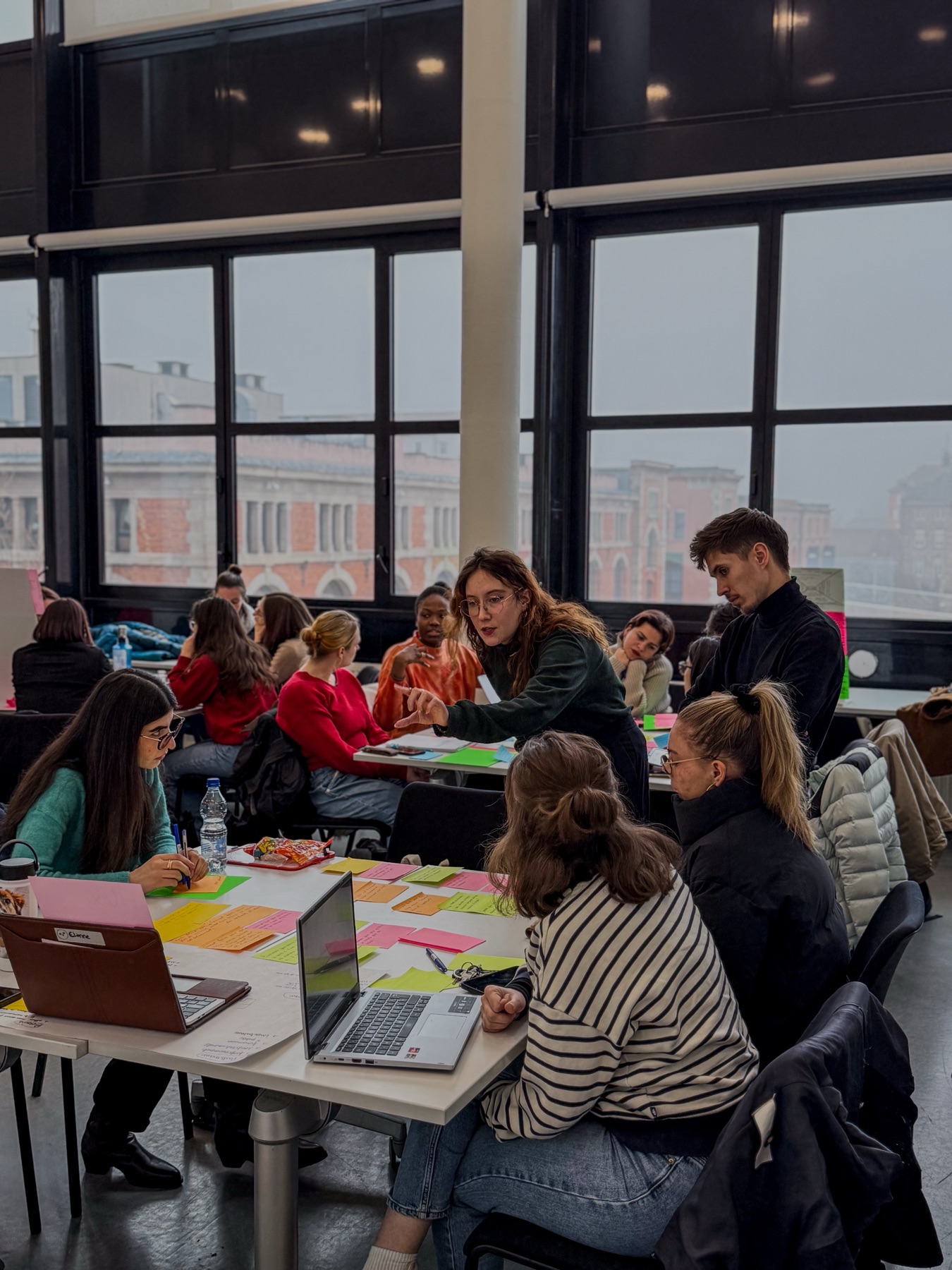 Grande salle de travail, participants attablés avec post-it et ordinateurs