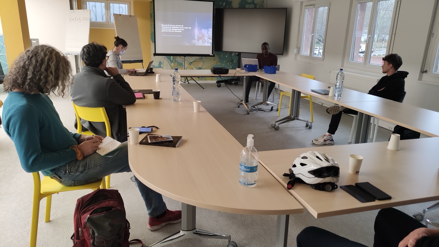 Salle de formation : participants attablés face à un écran de projection