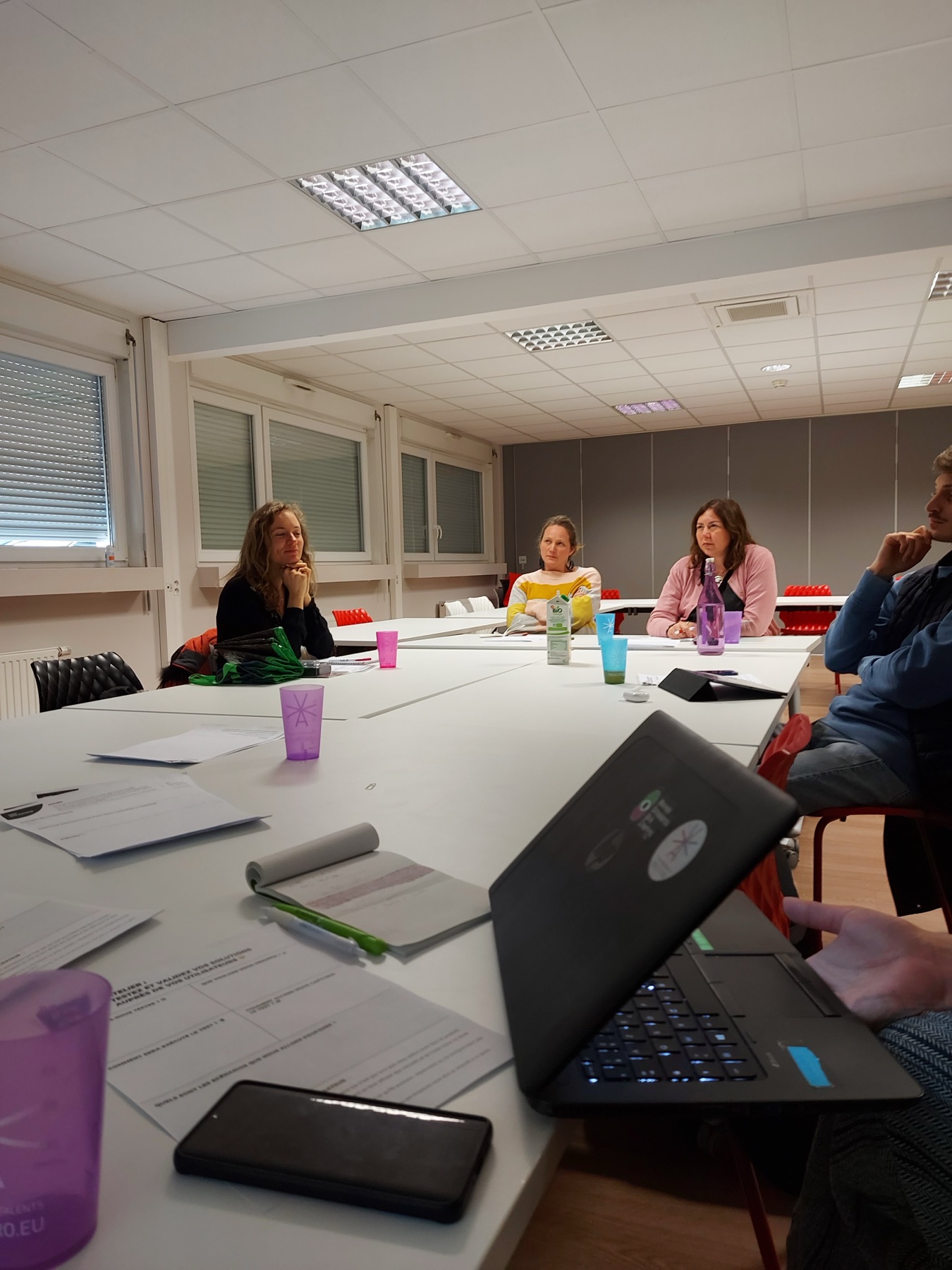 Séance de travail autour d'une grande table, ordinateurs et carnets ouverts