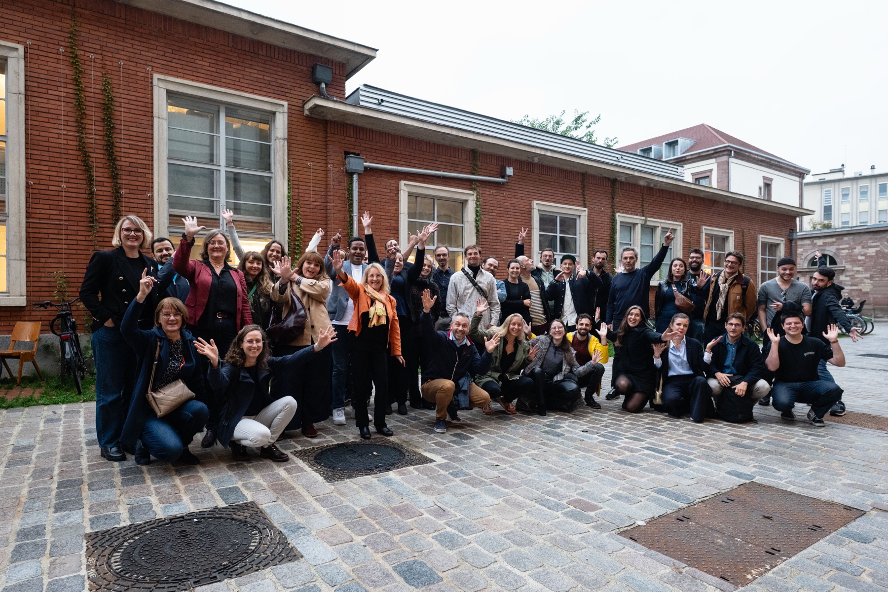 Photo de groupe des lauréats et partenaires Tango&Scan, bras levés dans une cour pavée